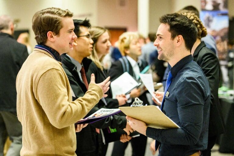 recruiter and student talking at a career fair among a crowd of other people