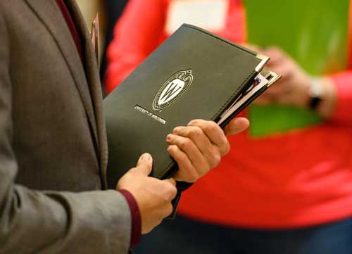 close-up of a UW notebook held by a person with a suit coat on