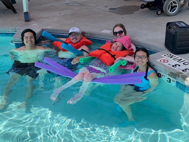 campers at Easter Seals respite camp in a swimming pool with nursing student, all smiling