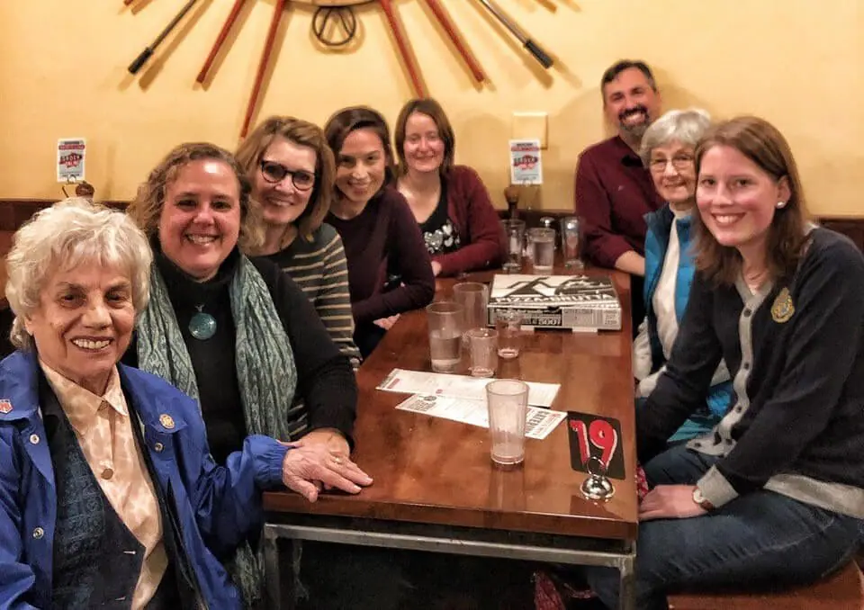 group of people sitting at a table in an Italian restaurant, smiling at the camera