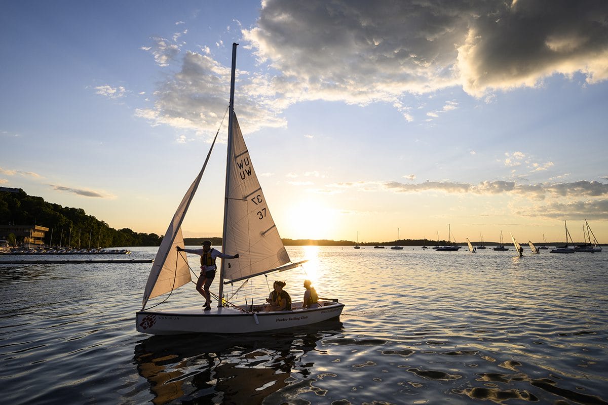 Seen from the Memorial Union Terrace at the University of Wisconsin-Madison, members of the Hoofers Sailing Club sail their boat on Lake Mendota as the late spring/early summer sun sets.