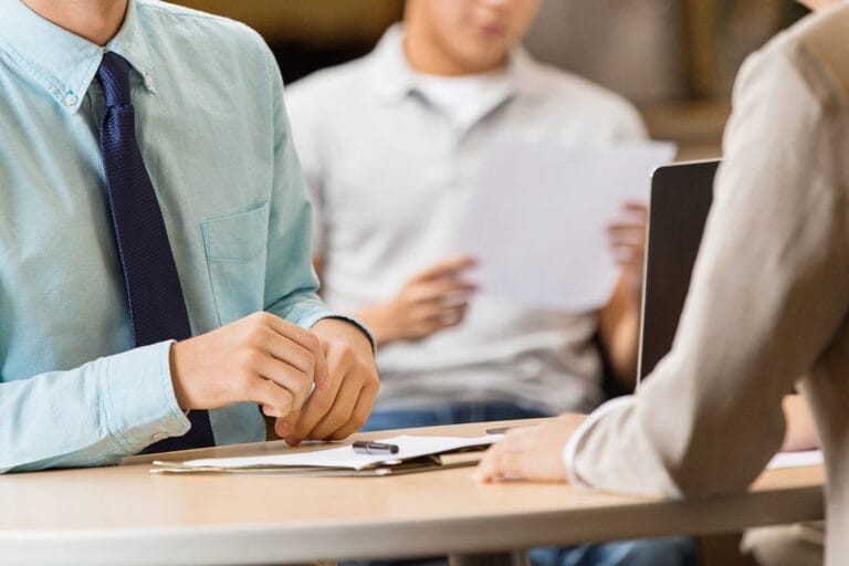 students -- one with a tie on -- sitting around a laptop