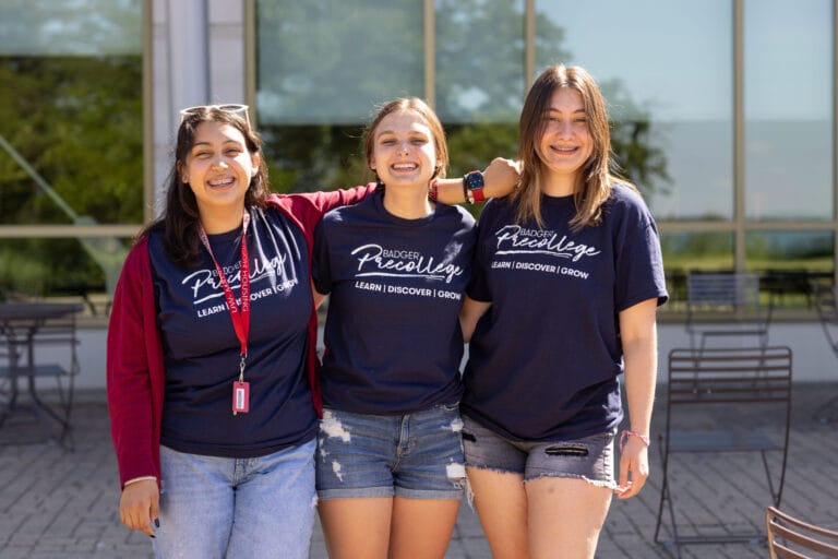 Three precollege students smiling as they take a selfie.