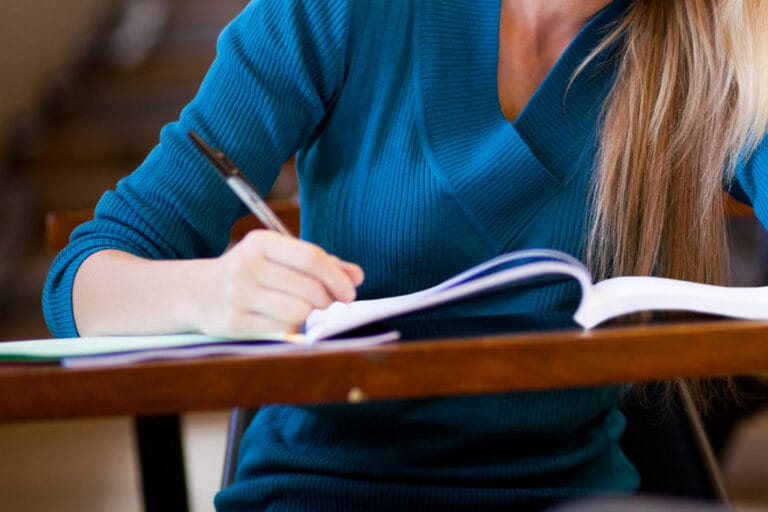 Student writing at desk