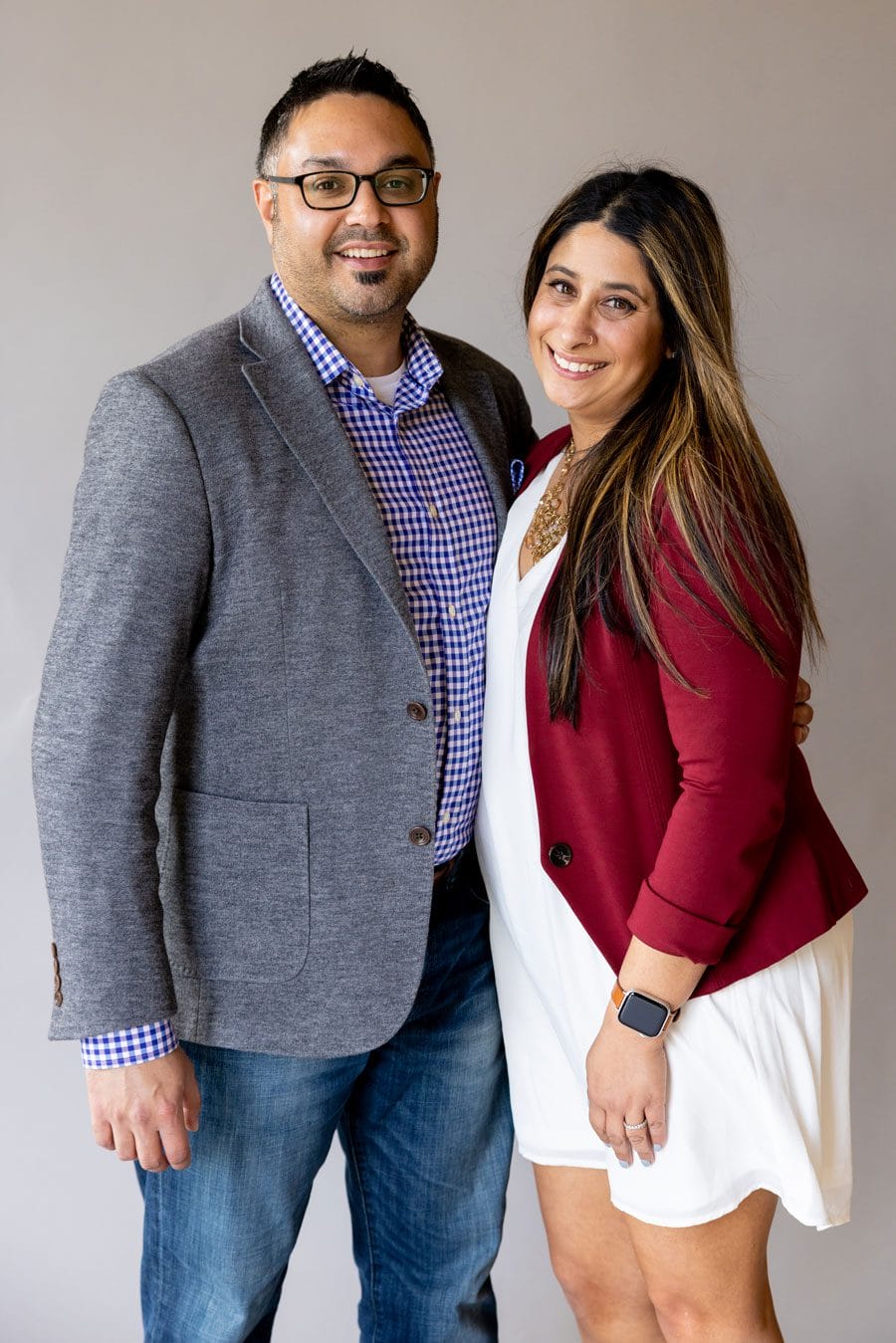 Student in blazer and formal dress stands beside her partner, both smile 