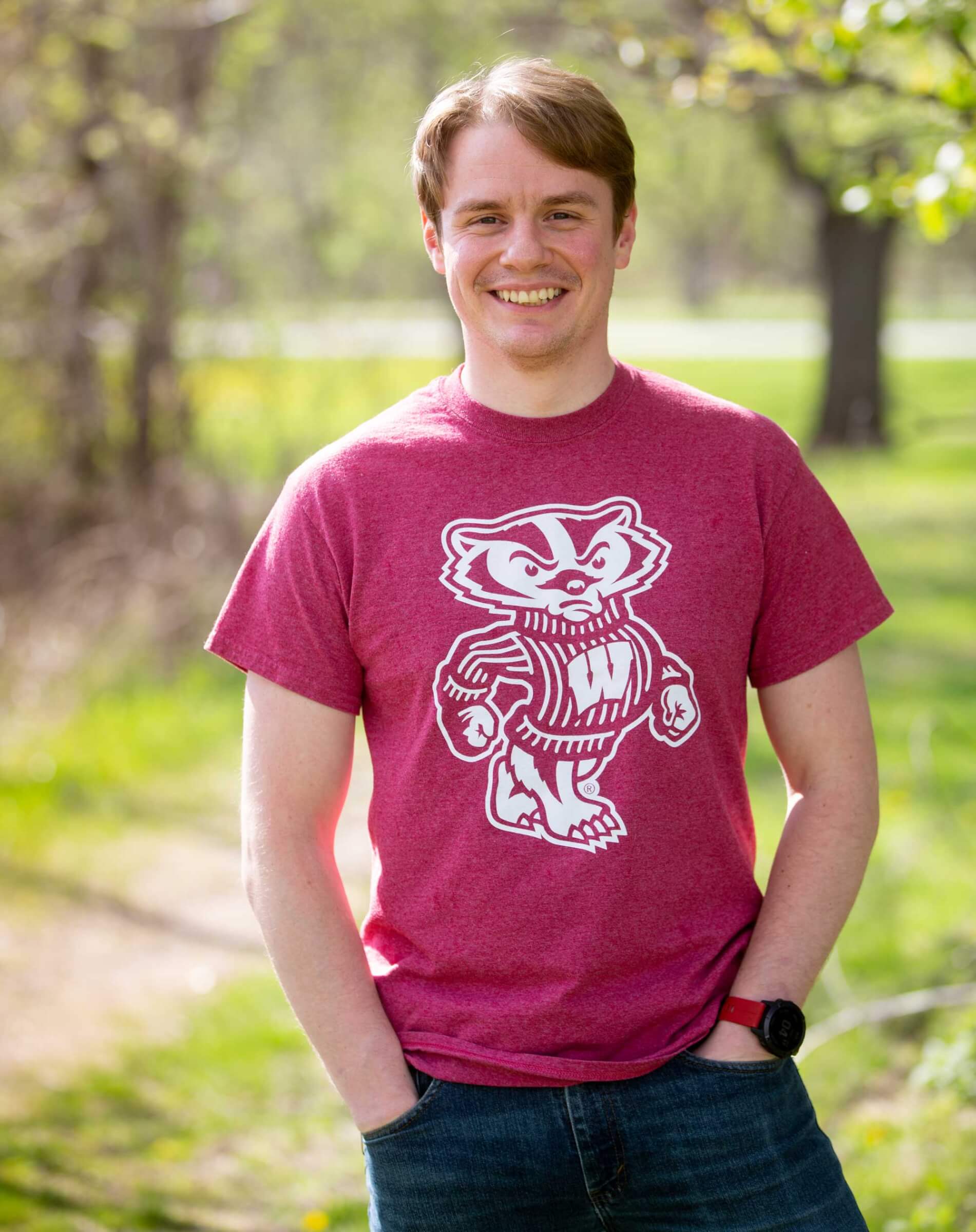 Dan Gerstl smiling with his hands in his pockets in a bucky badger shirt