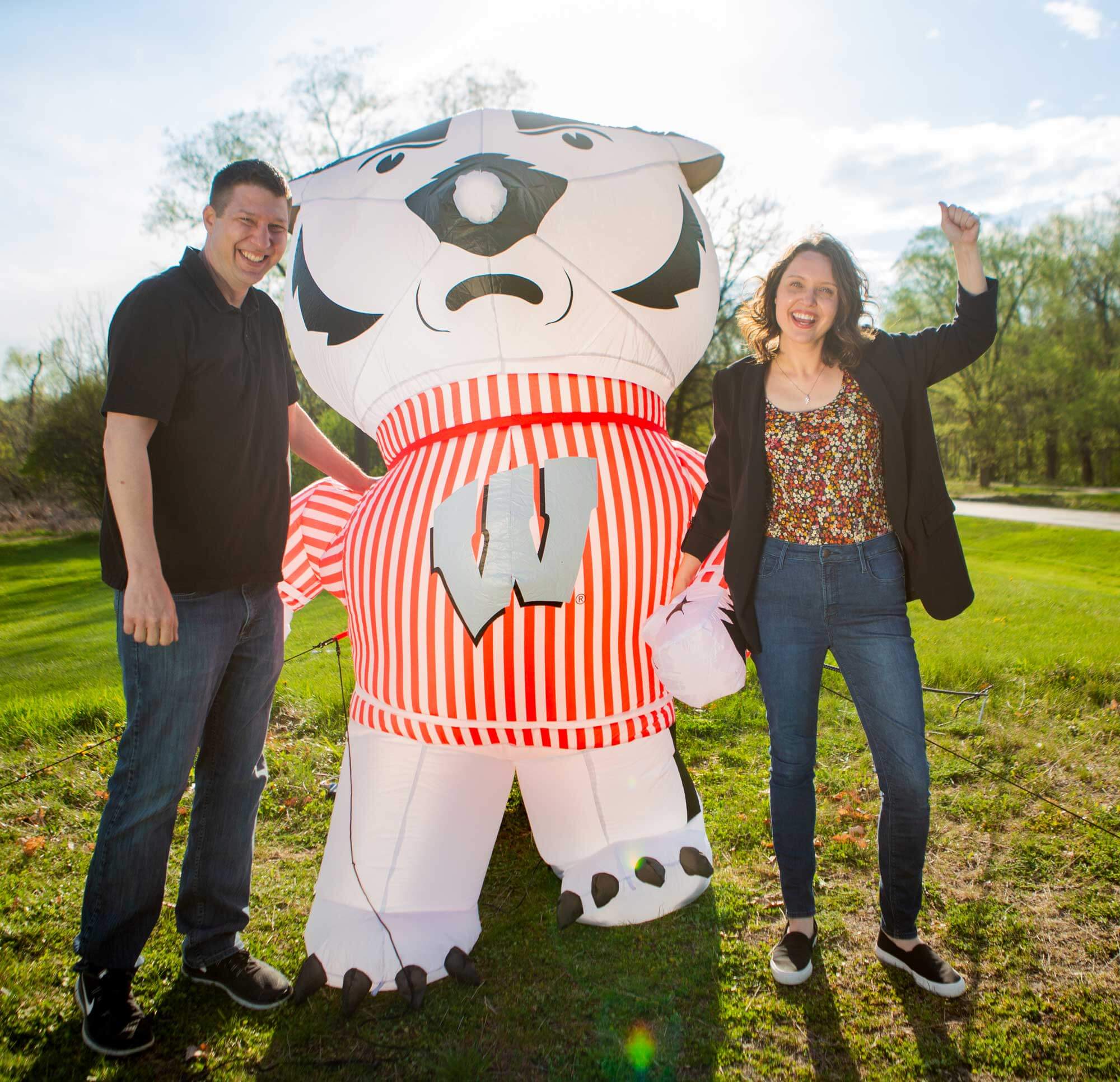 Kassandra Gossens and partner standing next to blow up Bucky Badger