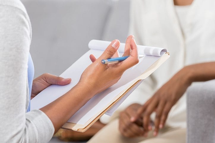 A closeup of two peoples hands. One is speaking and taking notes.