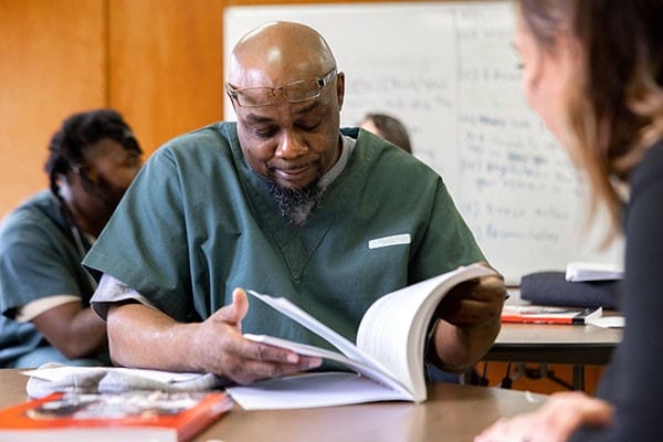 Michael sits at a table in the prison, studying