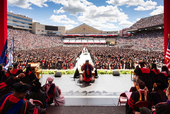 person on graduation stage speaking to a large crowd