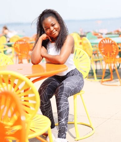 Zephirine Zoungonou sitting on a yellow terrace chair in front of the lake