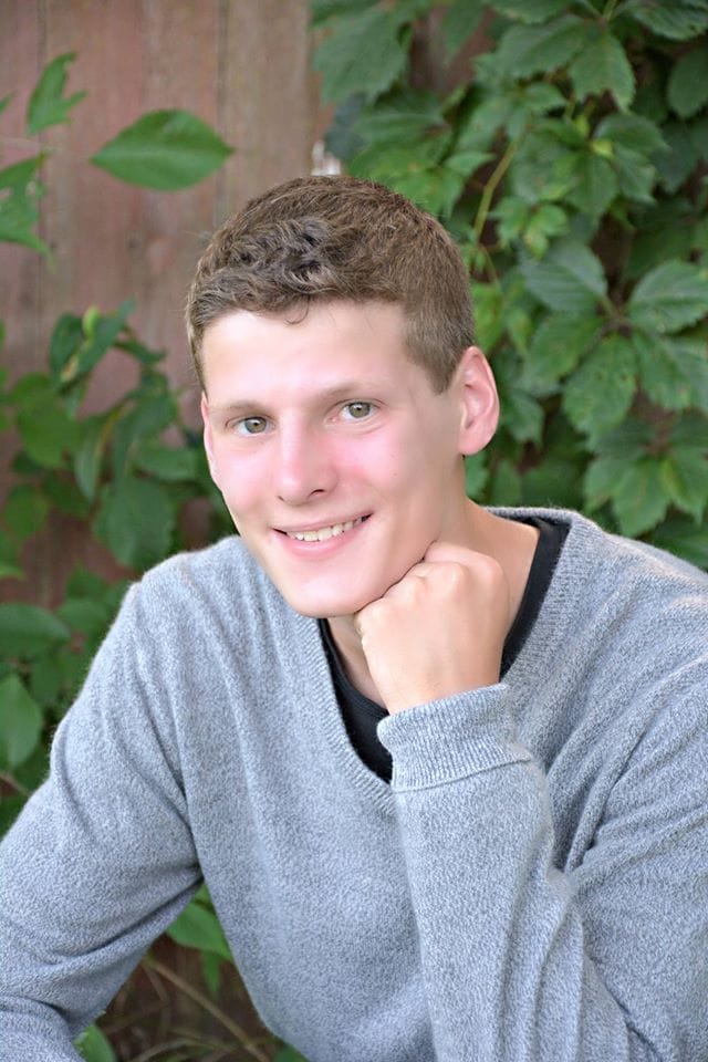 Portrait of a young man wearing a gray sweater.