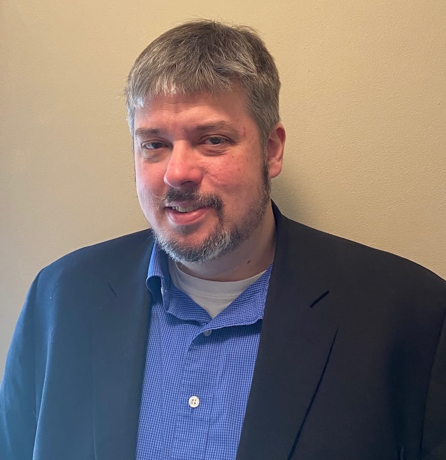 Jason Glomp, UW–Madison returning adult student, has salt and pepper gray hair and is wearing a blue collared shirt and navy suit jacket.