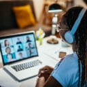 A student wearing headphones looks at her laptop during a video chat.