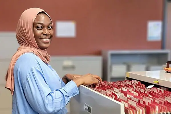 Fatima Abdul Rasheed going through files in a filing cabinet.