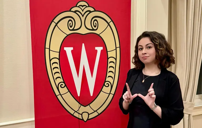 Ivanna Ceballos standing beside a UW-Madison flag