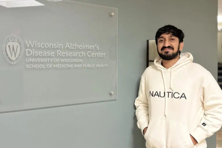 Rahil Virani standing next to a UW-Madison plaque