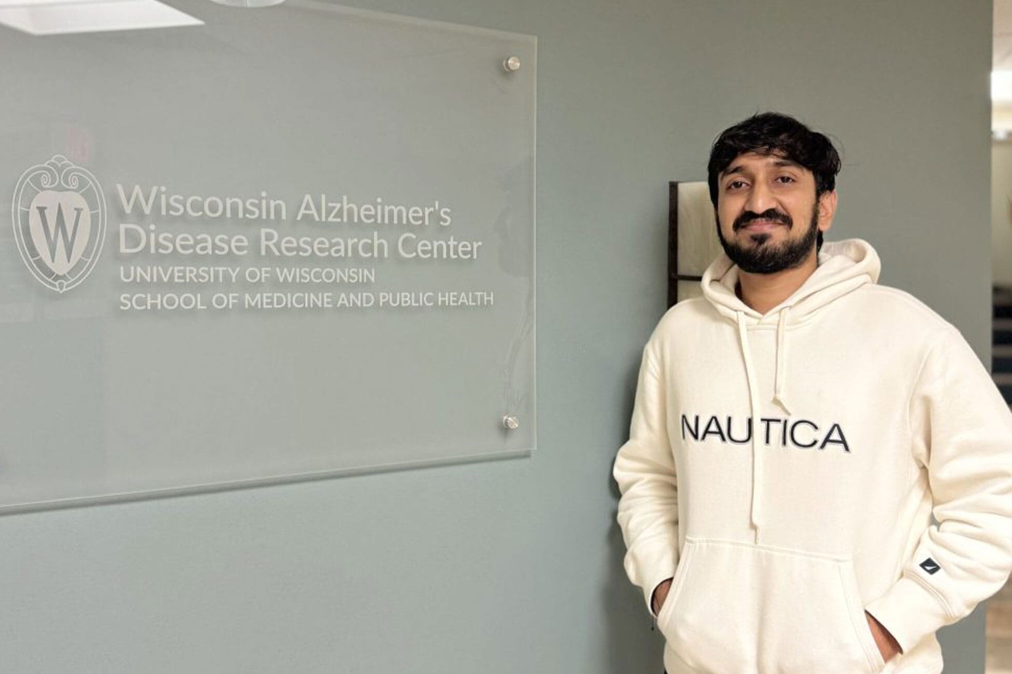 Rahil Virani standing next to a UW-Madison plaque