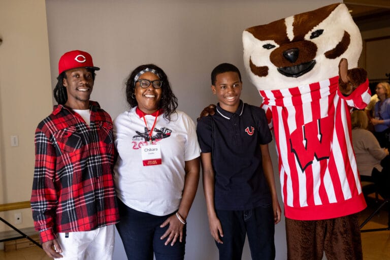 Group photo of graduate Chikara Crooks and her family posing with Bucky Badger
