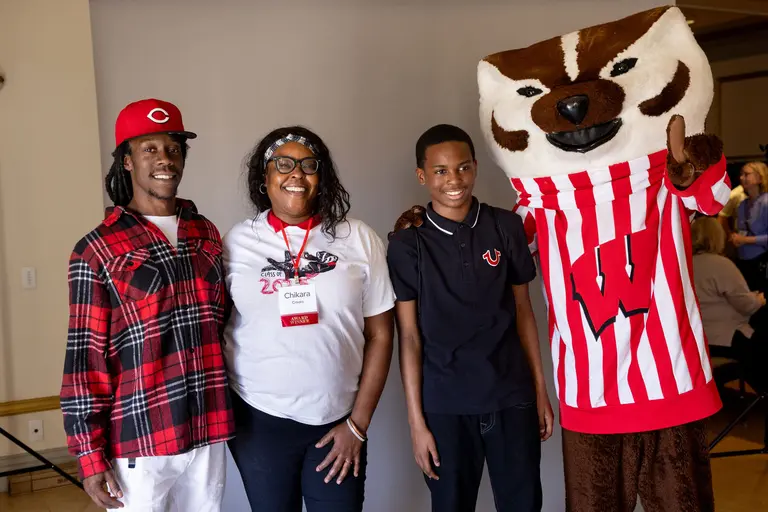 Group photo of graduate Chikara Crooks and her family posing with Bucky Badger