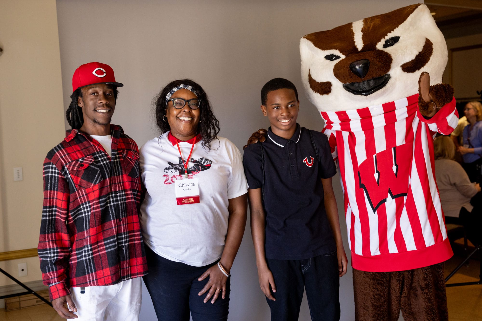 Group photo of graduate Chikara Crooks and her family posing with Bucky Badger