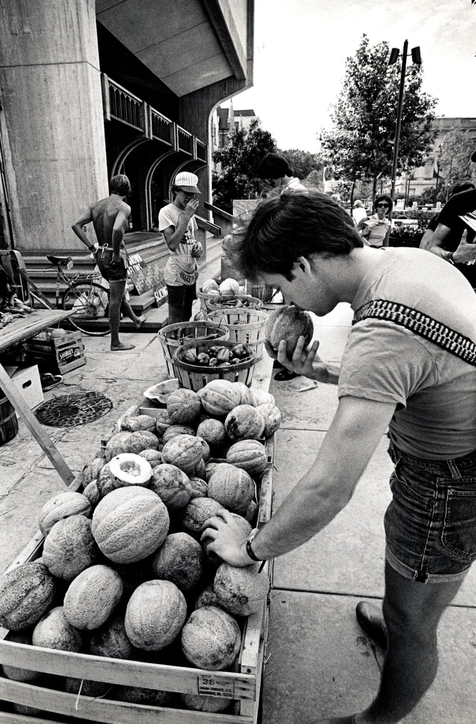 A man examining a piece of produce at a farmers' market.