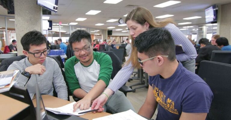 A trio of engineering students reviewing data with their professor