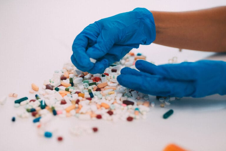 A pair of gloved hands sorting through various pills