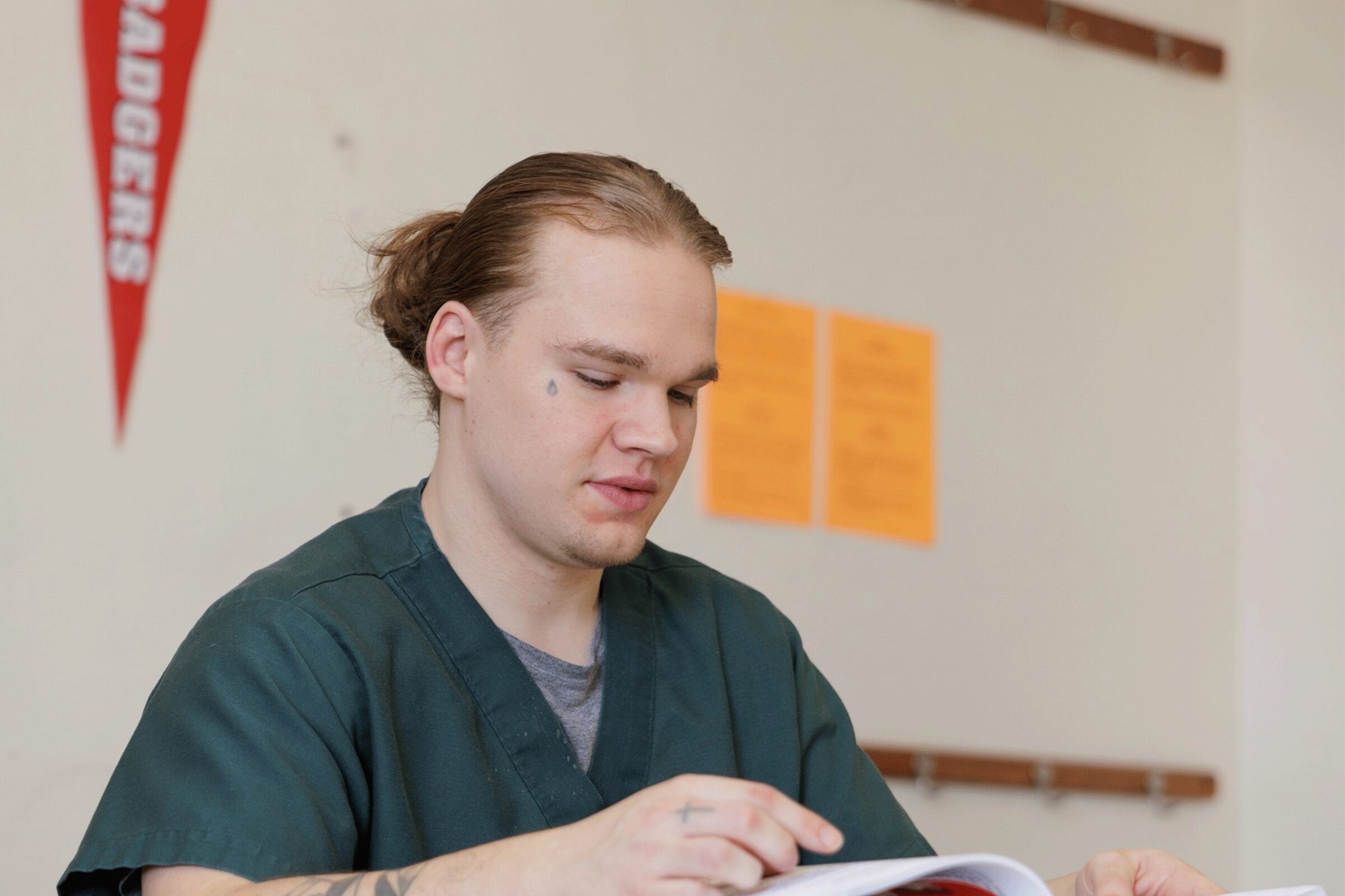 Odyssey Beyond Bars student in a classroom, flipping through a book.