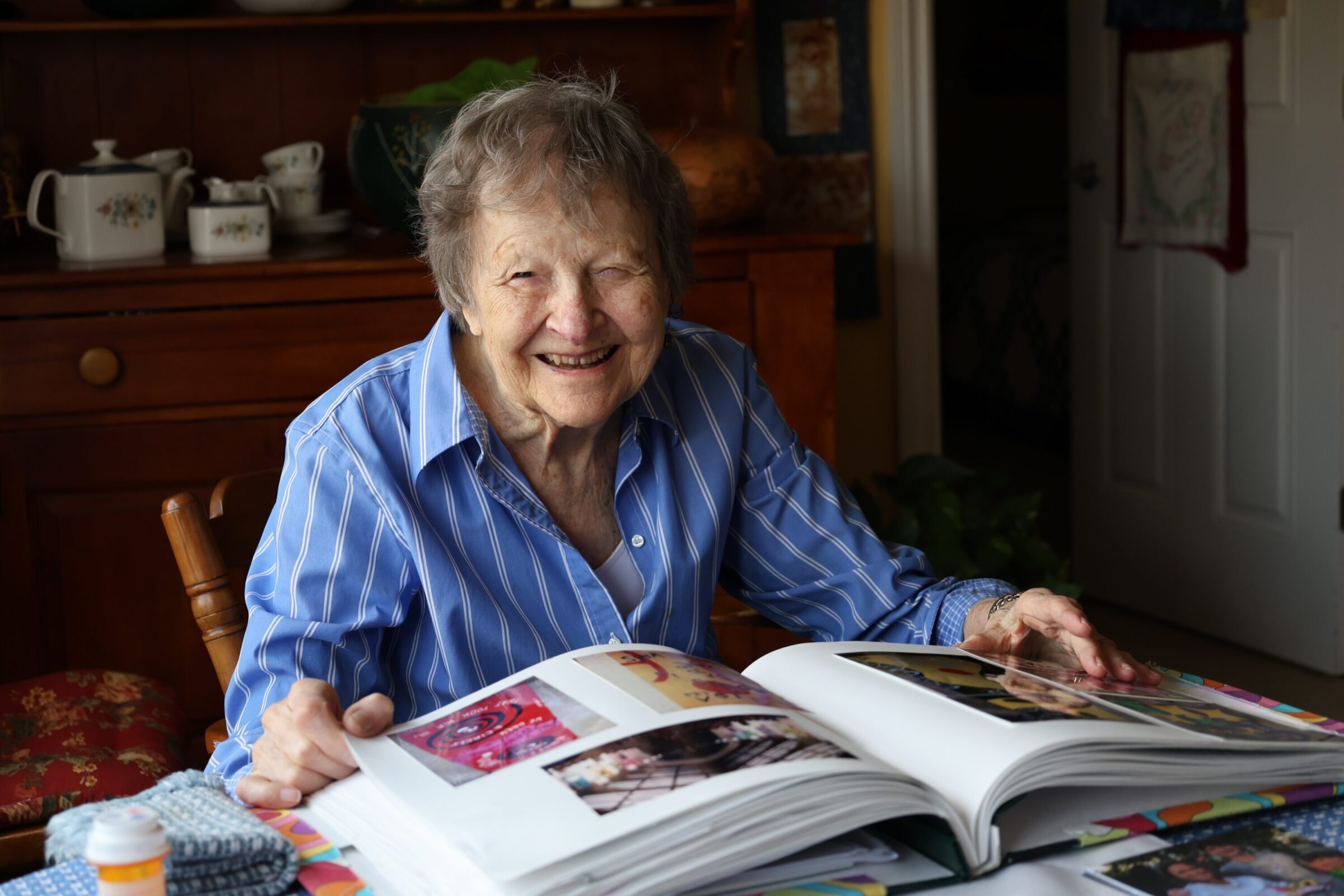 Marge Engelman sitting at her kitchen table, flipping through her scrapbook
