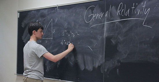 Badger Precollege student writes on large chalkboard