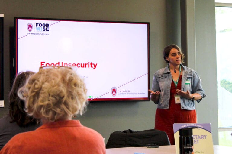 Liz Murphy stands at the front of a classroom, giving a presentation on food insecurity