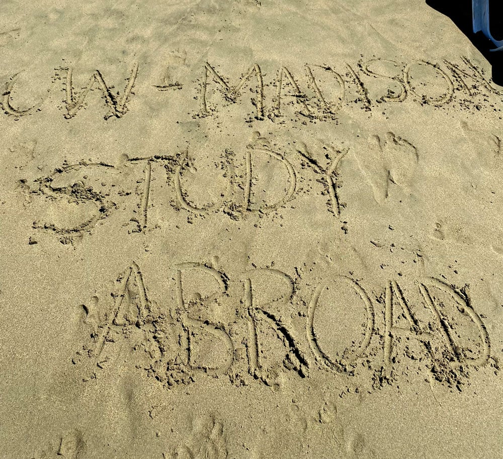 Writing in the sand spells out “UW–Madison Study Abroad"