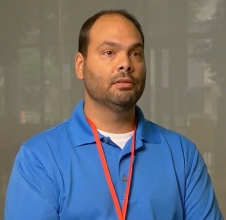 Man in blue polo shirt with orange lanyard.