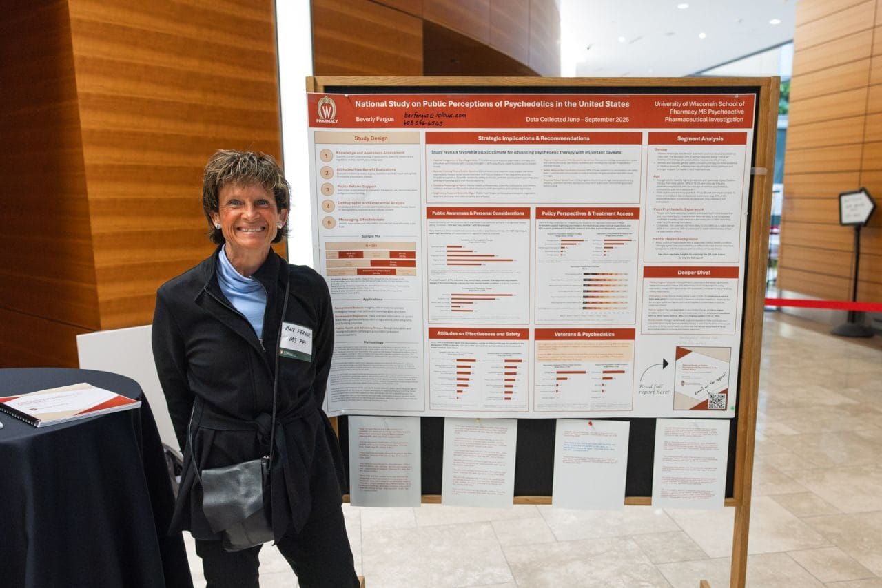 Woman standing next to poster at research symposium, smiling